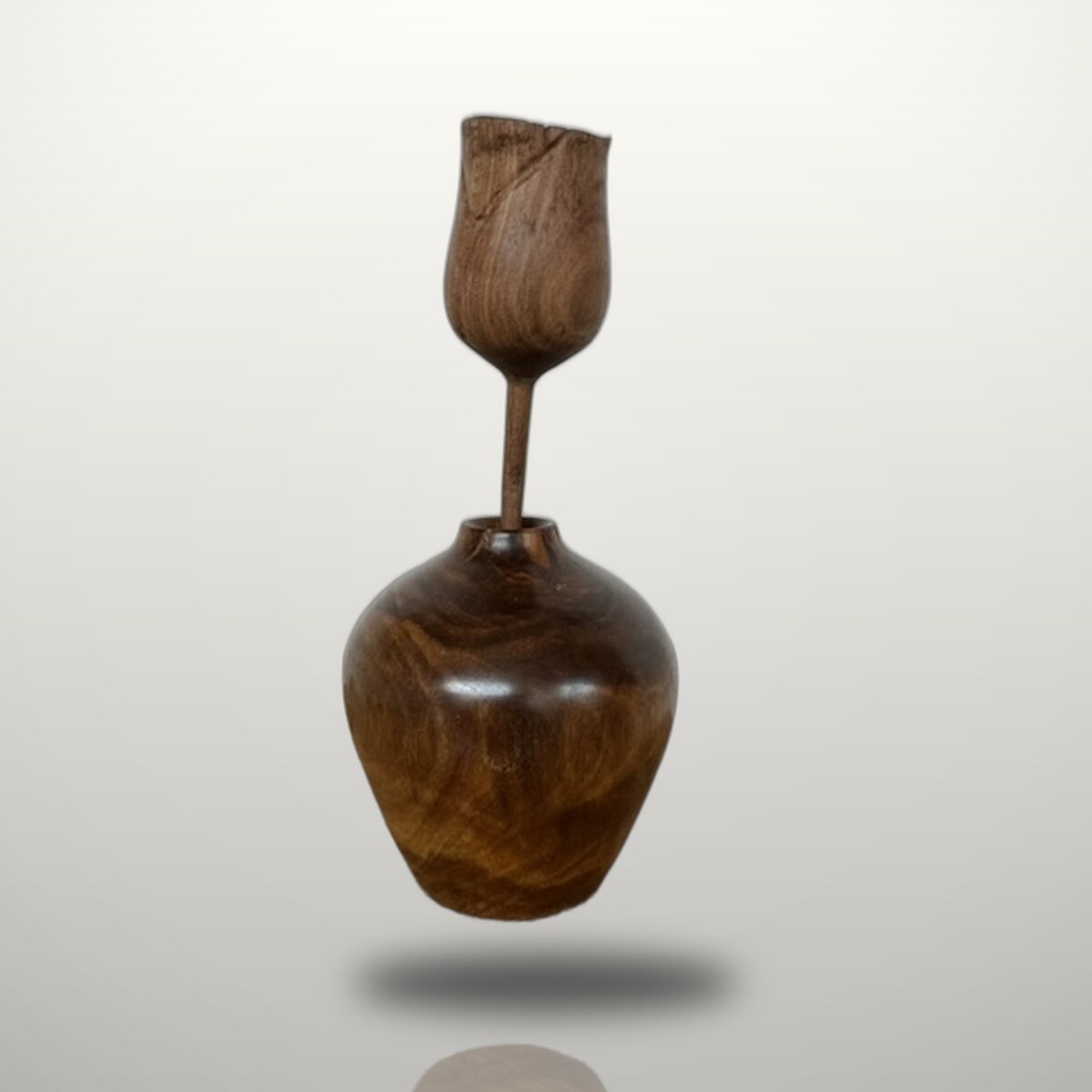 A slender turned lignum-vitae bud vase with a small carved wooden rose standing in it