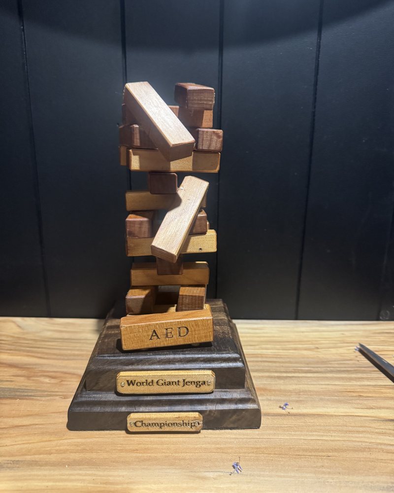 Giant Jenga championship trophy for a university department — stacked timber blocks on an engraved base